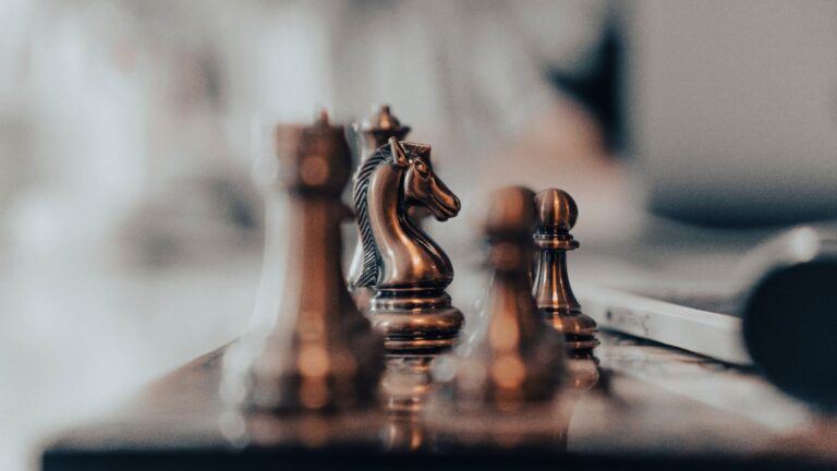 Close-up of wooden chess pieces on a board in warm tones