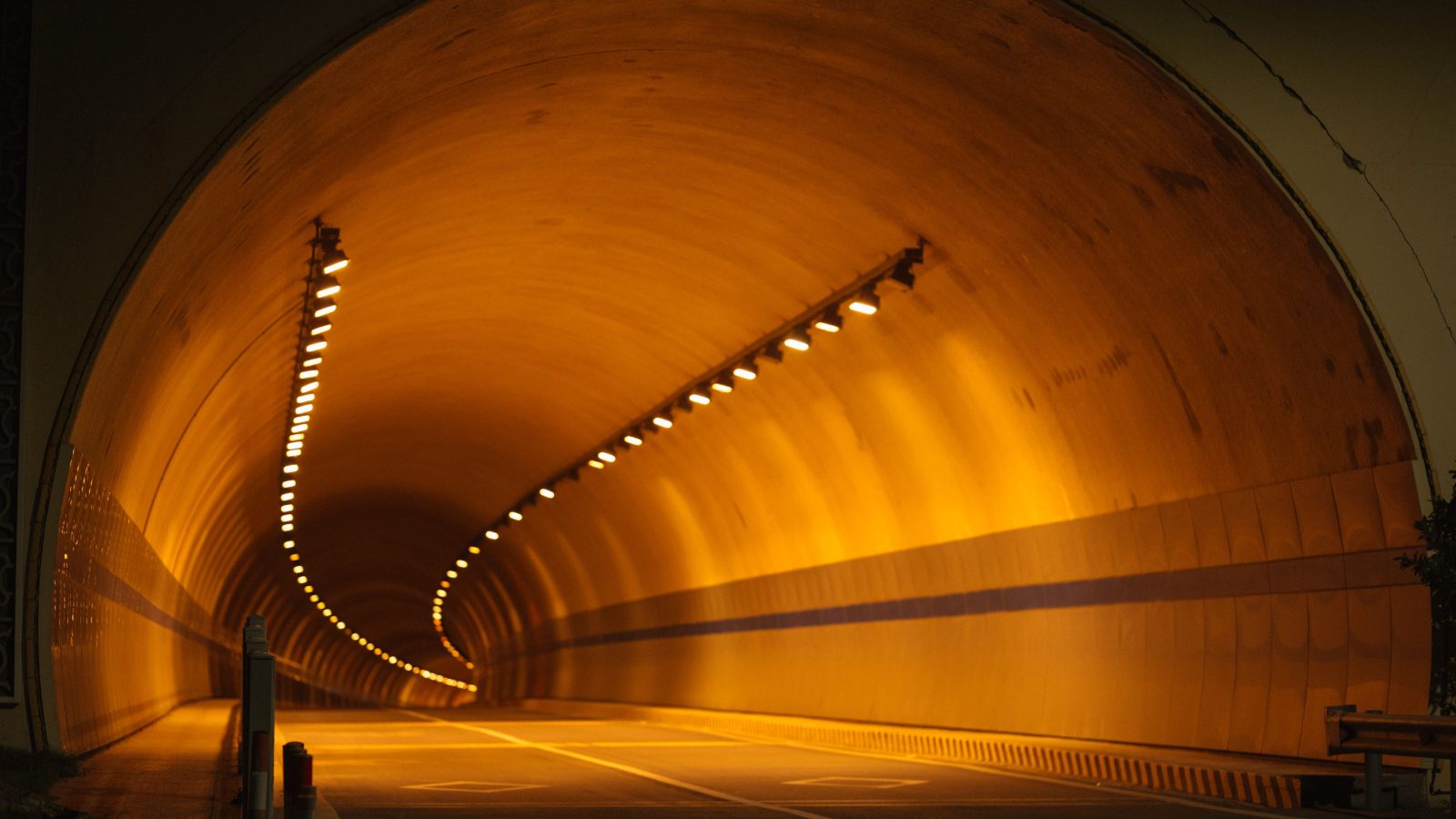 A long illuminated road tunnel with a curved perspective